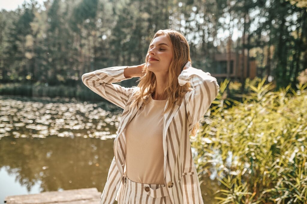 Beautiful relaxed long-haired woman on a river bank
